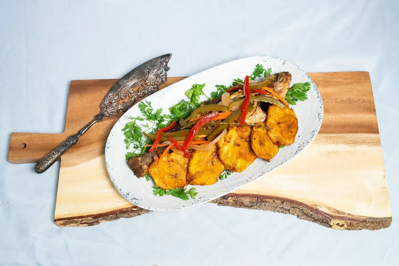 Whole fish with plantains and peppers on a serving board